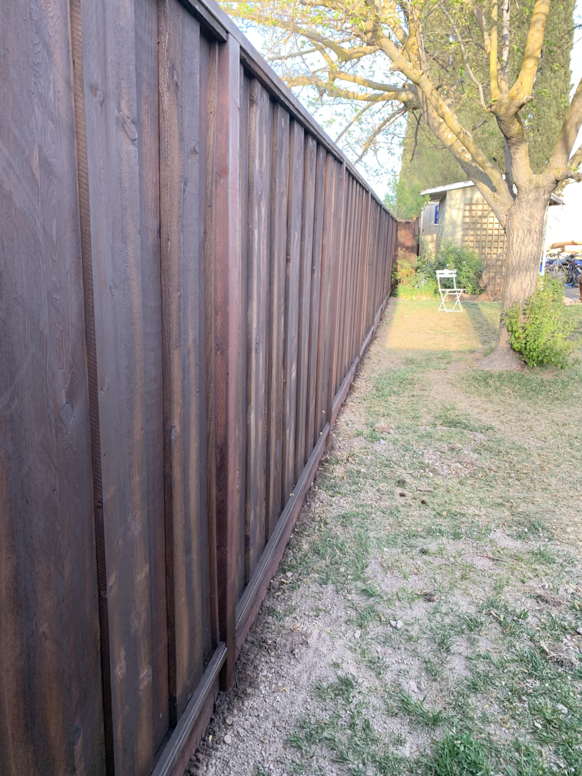 Long dark stained redwood privacy fence built for a residential backyard by Cut Once Construction.