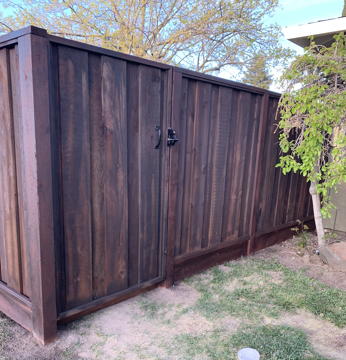 Dark stained redwood side gate and privacy fence with black gate hardware by Cut Once Construction.