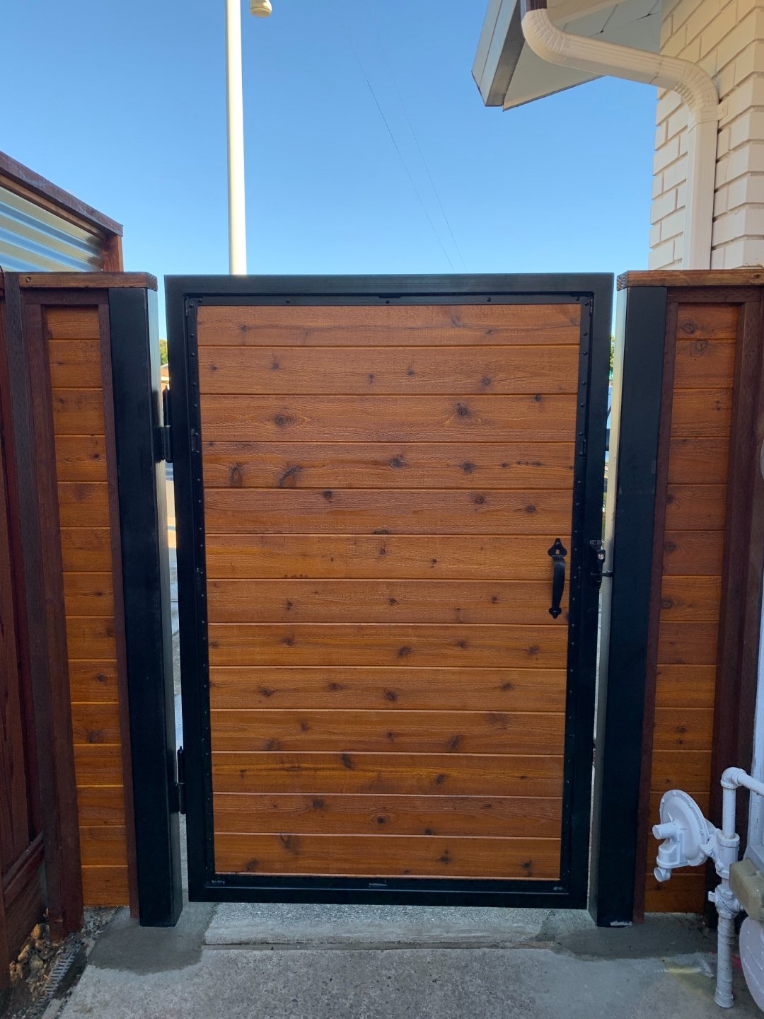 Steel-framed wood entry gate built by Cut Once Construction