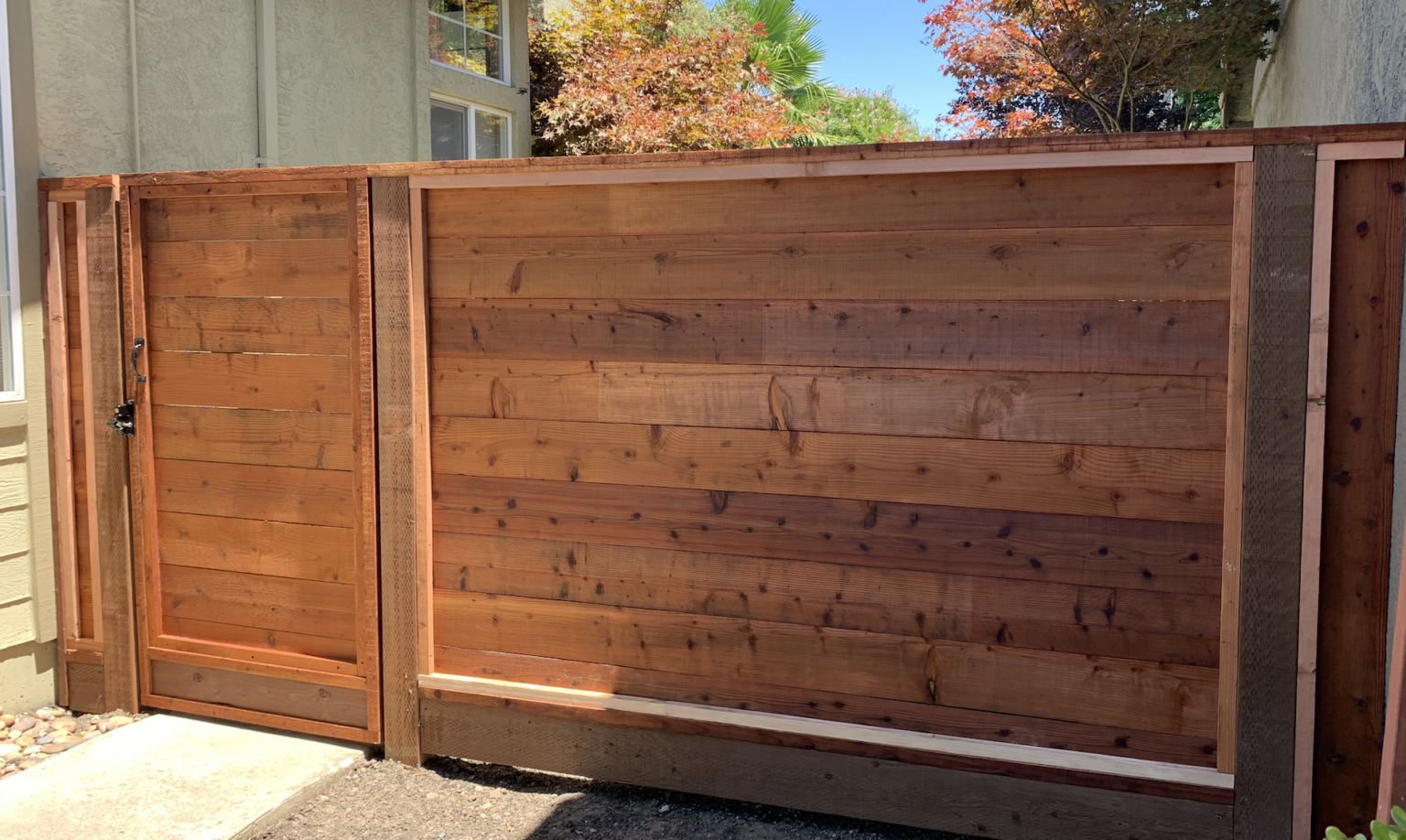 Horizontal redwood side gate and matching fence with black gate hardware.