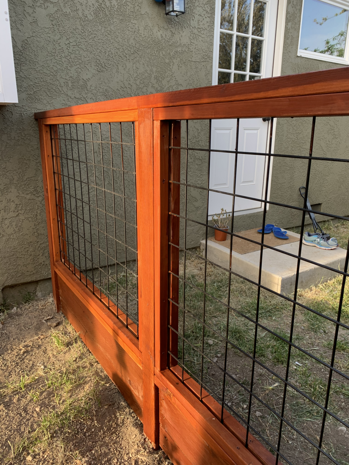 Close-up of redwood hog wire deer fence with framed wood posts and wire mesh.