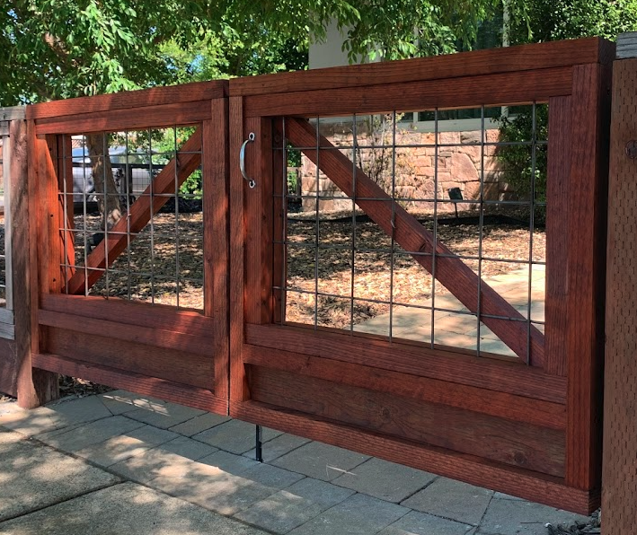 Redwood hog wire double gates with framed wood panels and metal wire mesh.