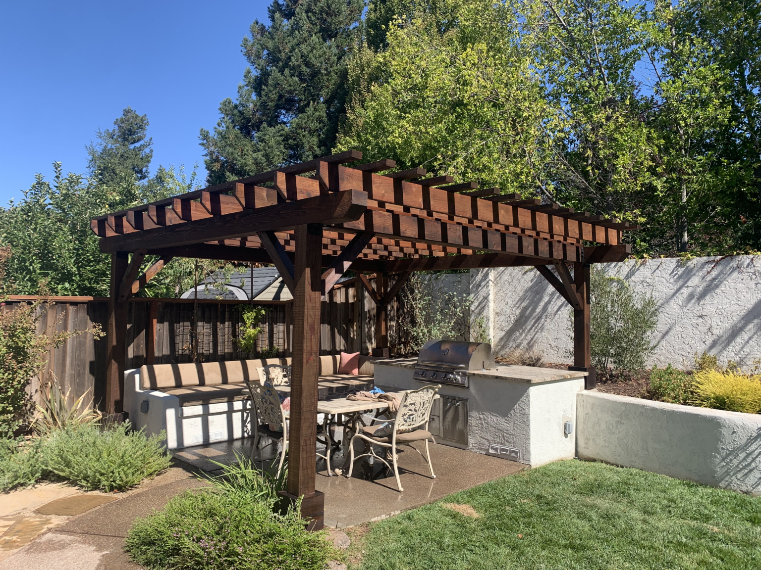 Redwood pergola built over an outdoor kitchen and backyard seating area.