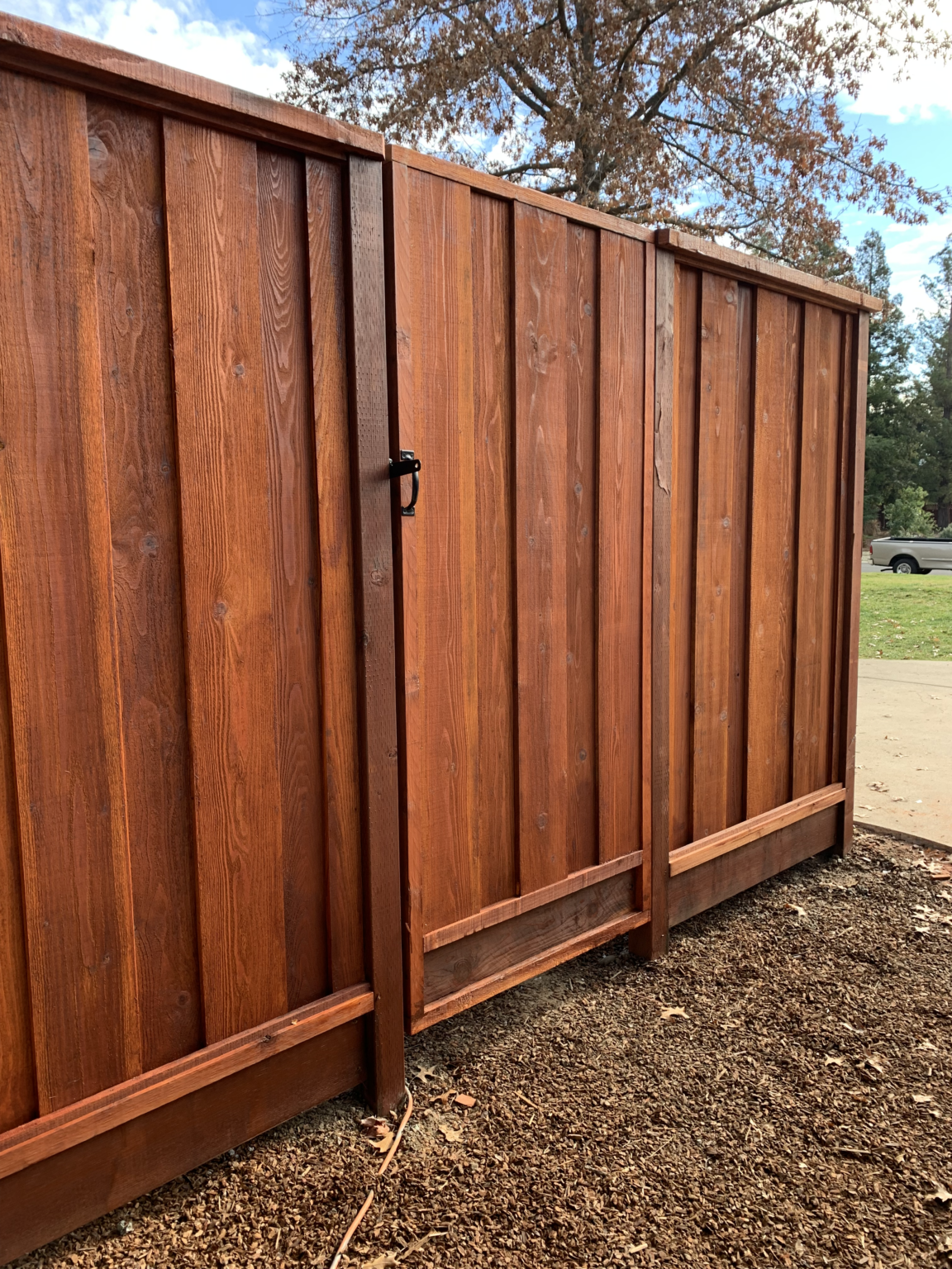 Redwood side gate built into a stained residential privacy fence.
