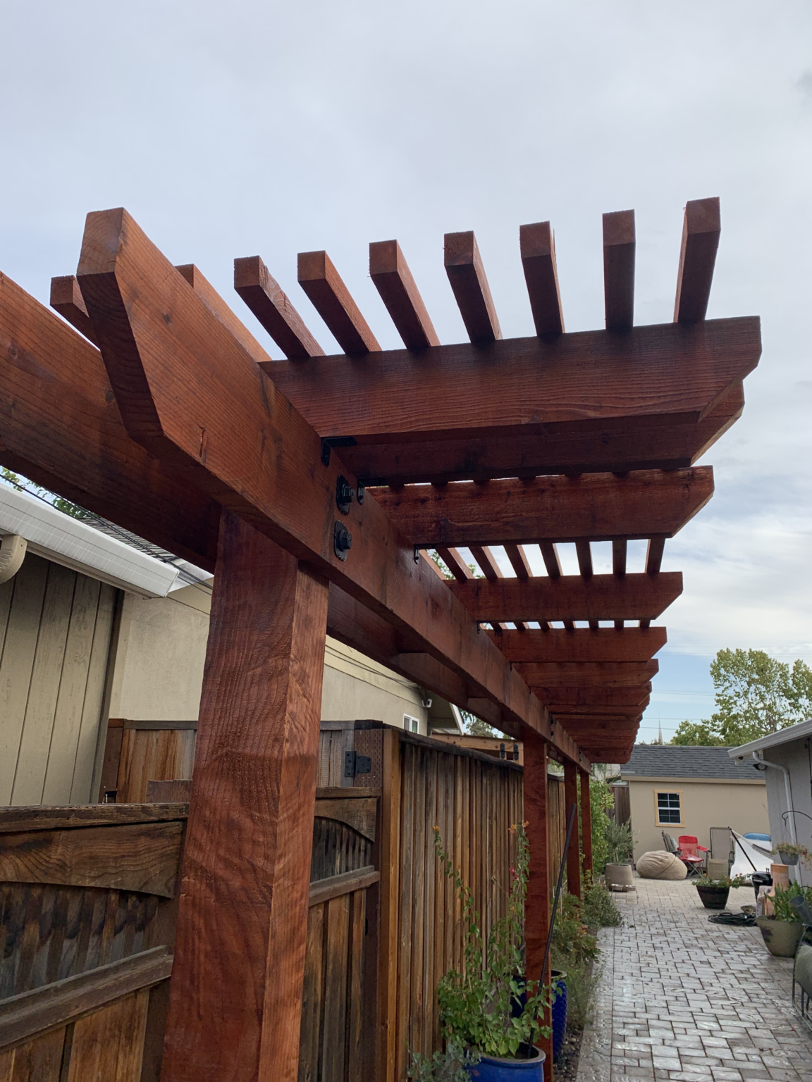 Redwood side yard trellis pergola with stained beams and posts.