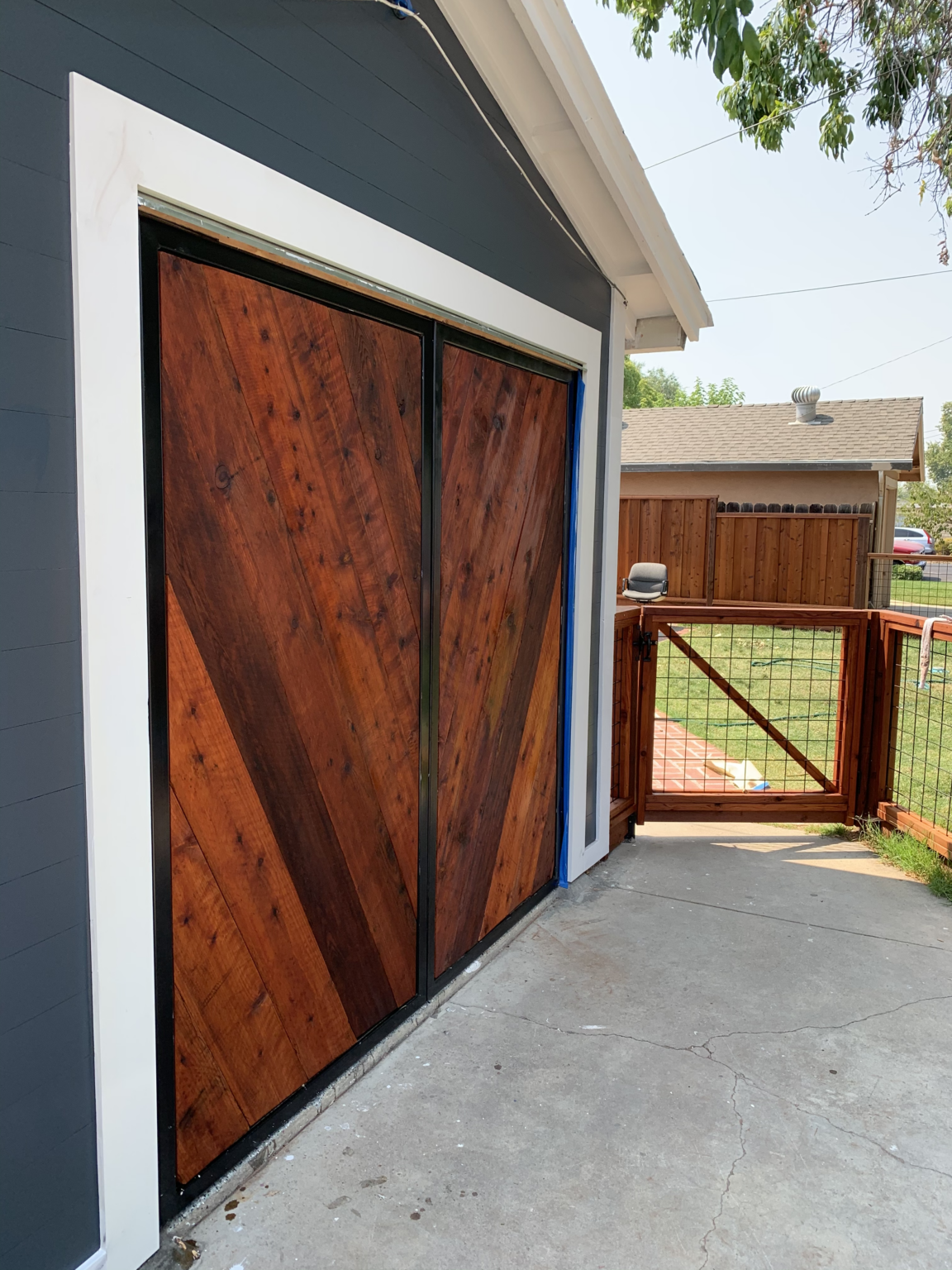 Steel-framed wood garage doors with diagonal stained wood boards and black metal frame.